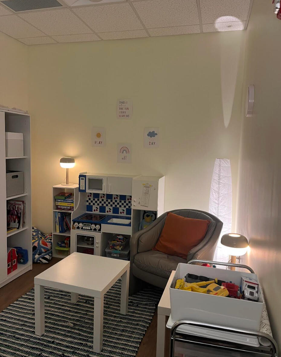 picture of an asian person in their 20's with shoulder-length black hair wearing a suit in greenery